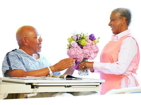 elderly woman giving flowers to elderly man
